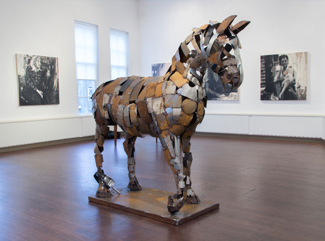 Groot paardensculptuur van hergebruikt metaal in een lichte tentoonstellingsruimte